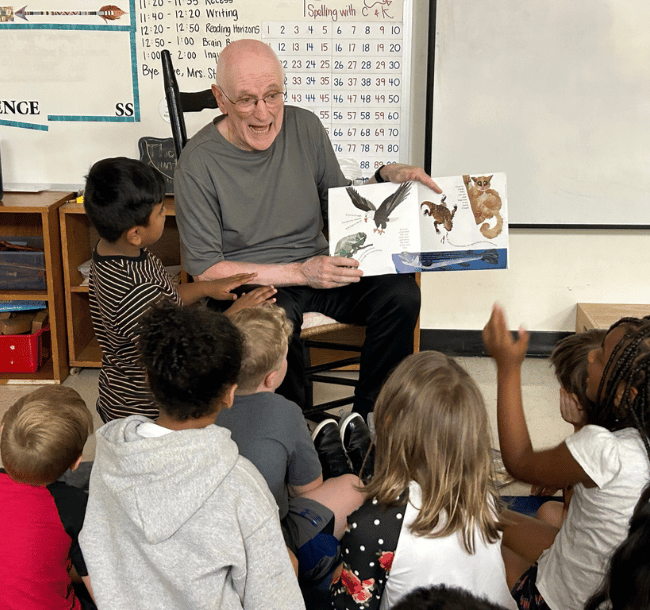 male reading buddy reads a storybook aloud to children