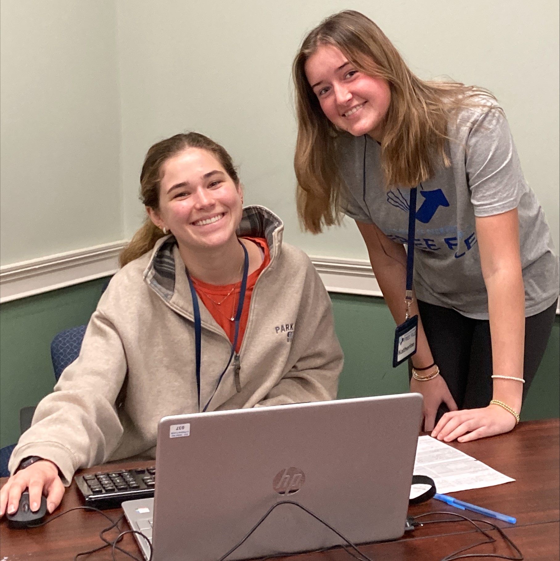 Two college students at a Free File tax site in smile in front of a computer