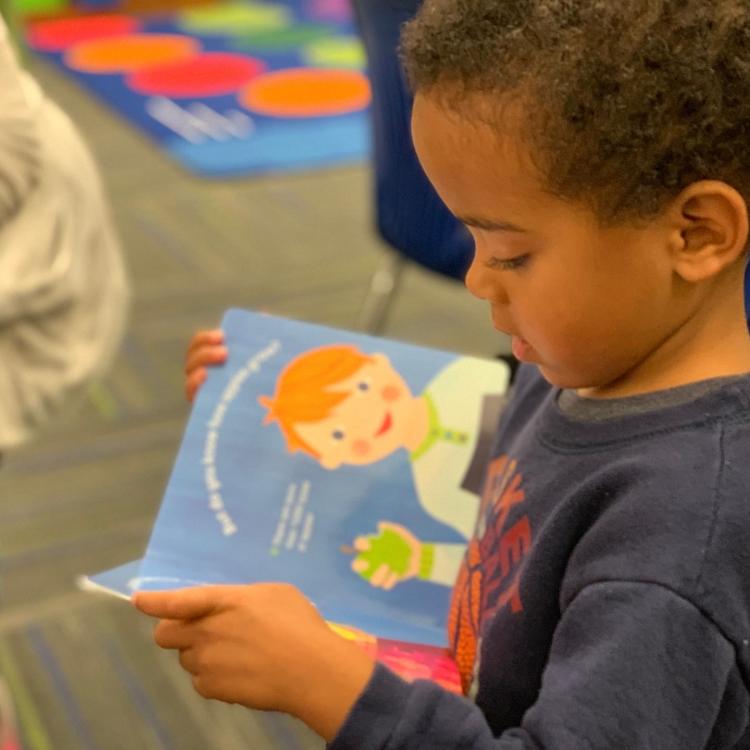 Toddler boy holding a book at Preschool Pages